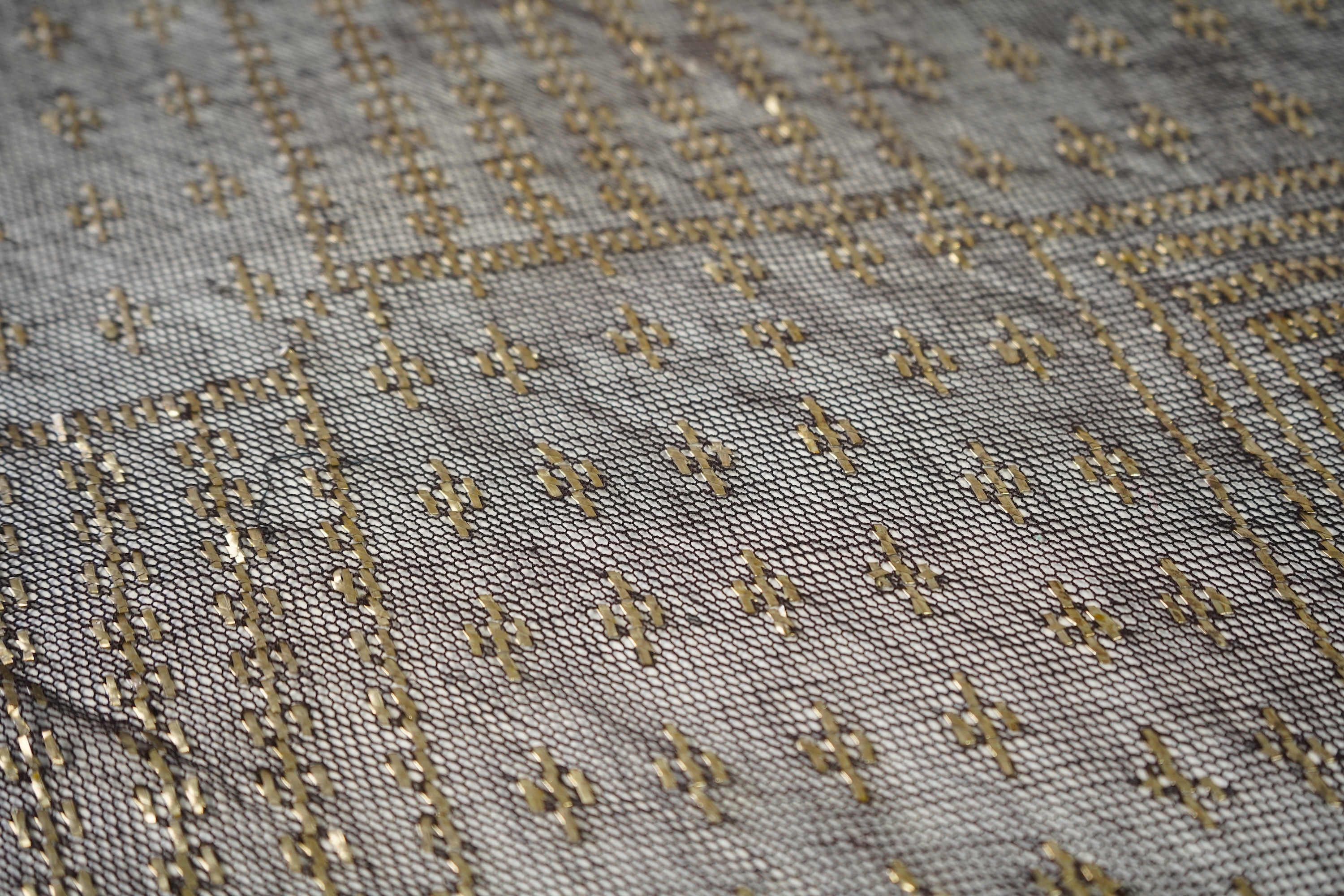 A 1930’s Egyptian decorative metal on black net evening stole. Approximately 218cm long. Condition - the rolled edges are frayed but the colour and design are intact.
